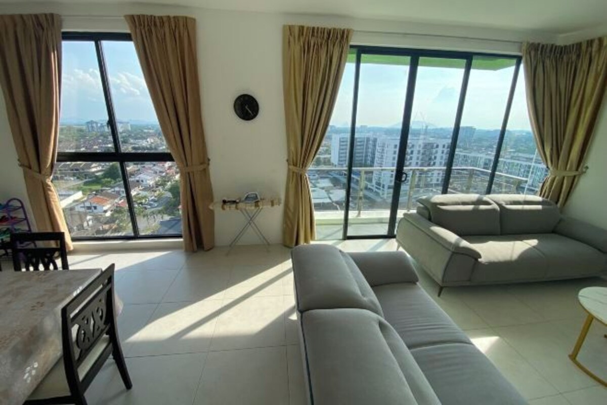 A living room with a sofa, a dining table, and a view of a cityscape through large windows.