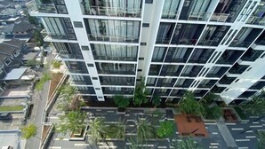 Un immeuble moderne de grande hauteur, doté de nombreux balcons et d’un jardin sur le toit.