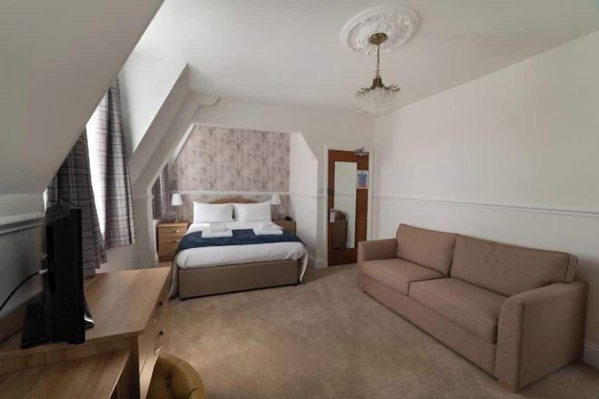 Une chambre à coucher avec un lit, un bureau, un canapé et un lustre.
