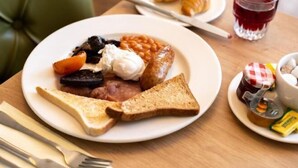 Une assiette de petit-déjeuner avec des toasts, des haricots, des œufs et des saucisses.