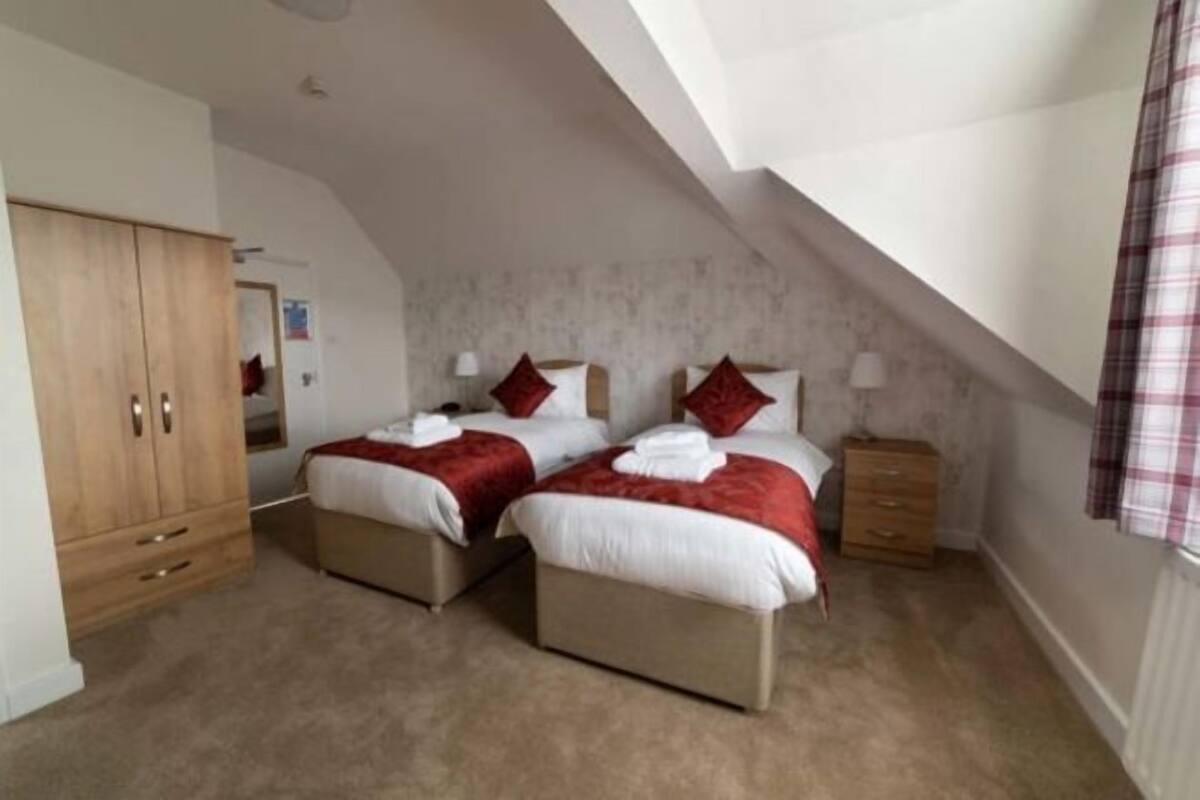 Une chambre avec deux lits, une armoire et une table de chevet.