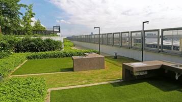 A rooftop garden with a seating area, a pathway, and a view of the city skyline.