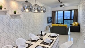 Un salon moderne comprenant un coin repas, un canapé, un téléviseur et une grande fenêtre.