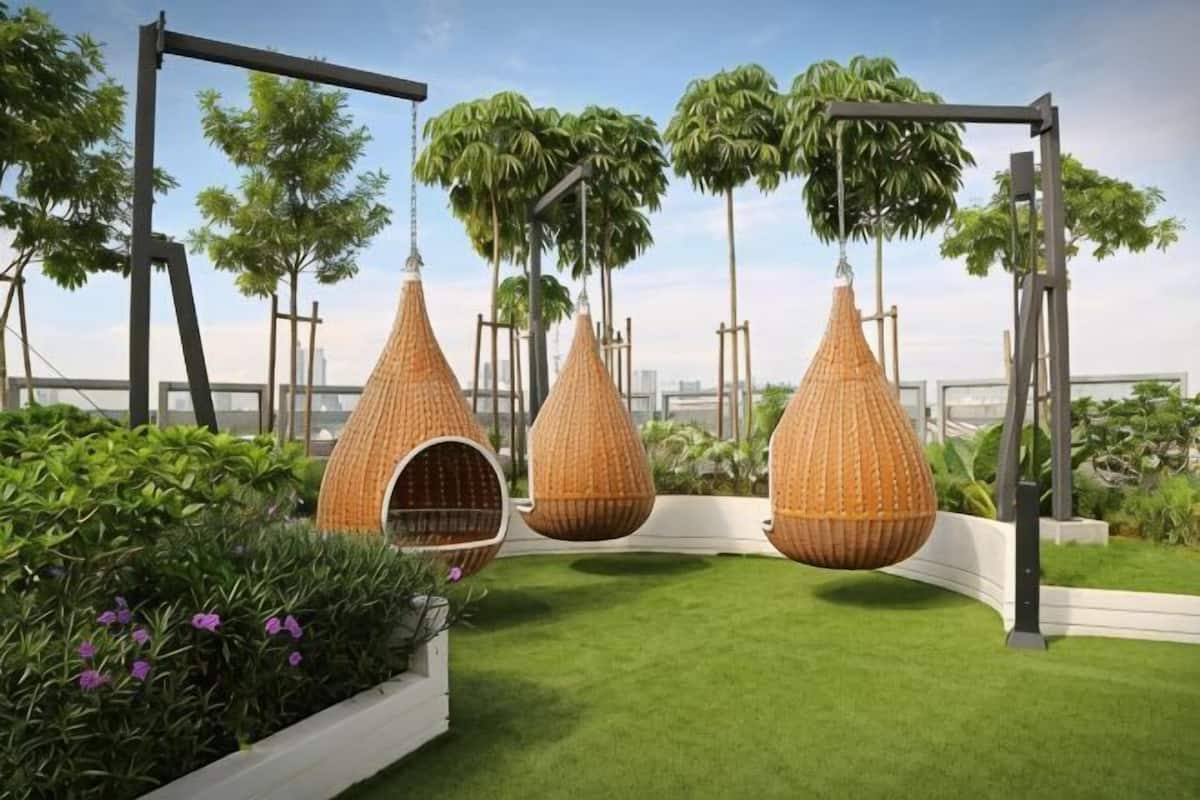 A rooftop garden with hanging wicker chairs, a swing set, and lush greenery.
