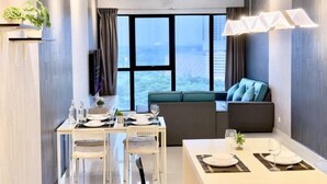 Une chambre d’hôtel moderne dotée d’un coin repas, d’un canapé et d’une grande fenêtre donnant sur la ville.