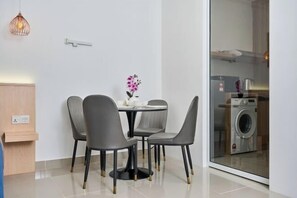 A modern room with a dining table and chairs, a small potted plant, and a washing machine visible through a glass door. - The Shore by HF Suites (Kota Kinabalu)