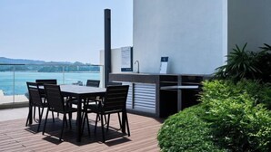 Une terrasse avec une table et des chaises, donnant sur une étendue d’eau.