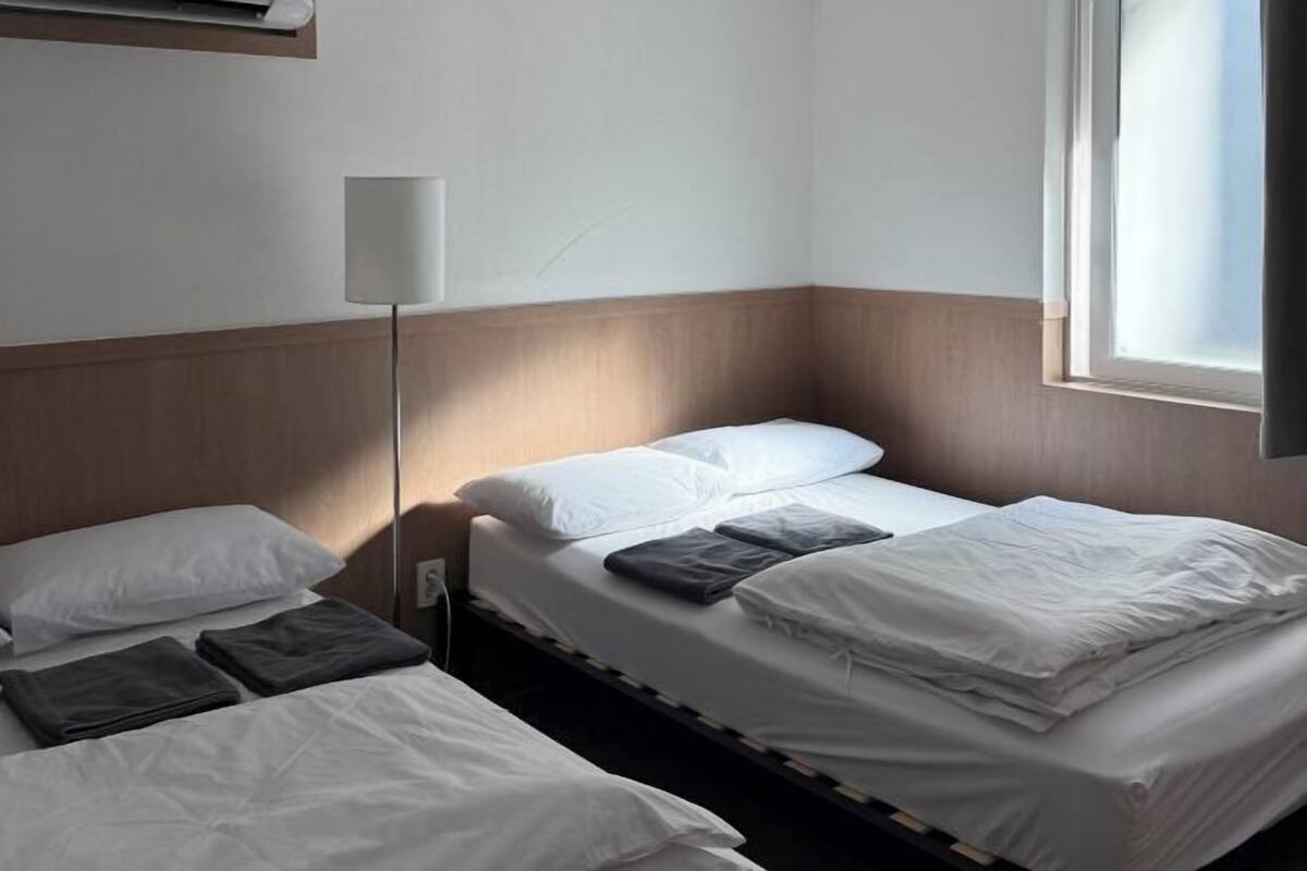 A hotel room with two beds, a bedside lamp, and a window.