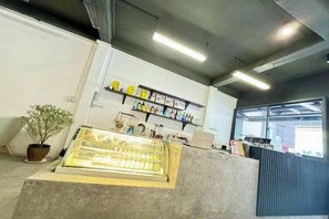Un espace d’accueil avec un comptoir, des plantes en pot et des étagères remplies d’objets.