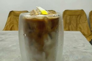 A glass of iced coffee on a table with a white surface. - Truman Hostel (Luang Prabang)