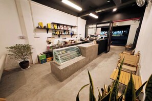 A cafe interior with a counter, seating area, and a display case. - Truman Hostel (Luang Prabang)