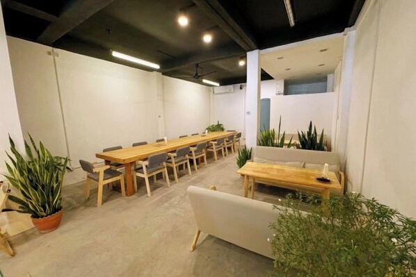 A conference room with a long table, chairs, and potted plants. - Truman Hostel (Luang Prabang)