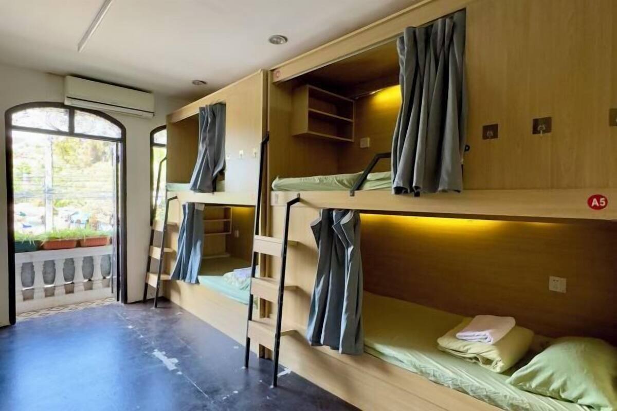 A bunk room with wooden bunk beds, a ladder, and a small shelf.