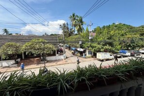 A street scene with a white truck parked on the side, a person walking, and a small kiosk with a blue umbrella. - Truman Hostel (Luang Prabang)
