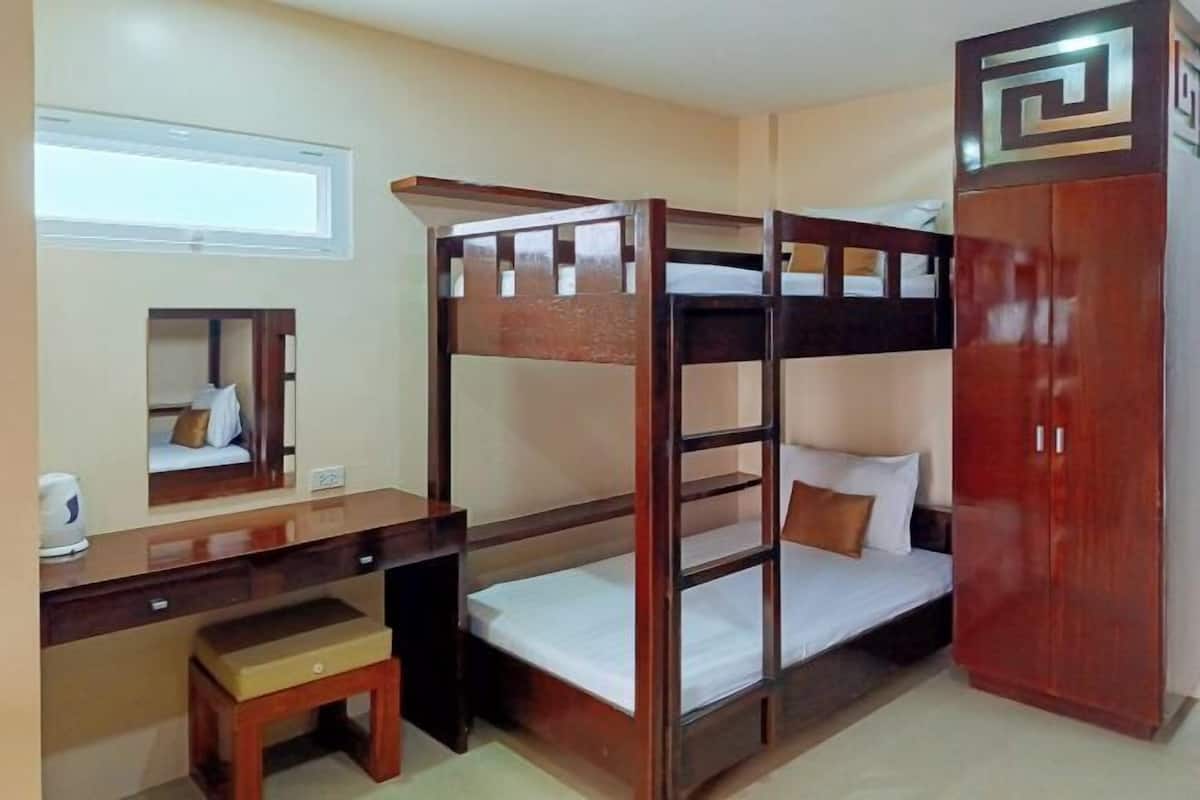 A bunk bed room with a desk, a chair, and a wardrobe.