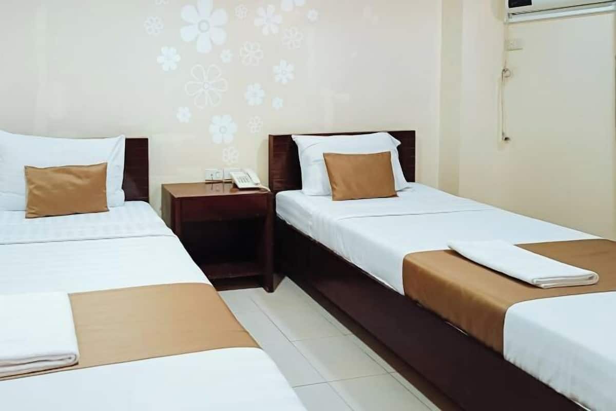 A hotel room with two beds, each with a brown bedspread and white pillows. There is a nightstand with a phone and a small table between the beds.