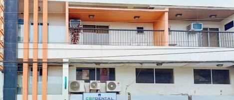 Um edifício de vários andares com espaço comercial no térreo, aparelhos de ar condicionado e fachada visível.