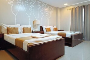 A hotel room with two beds, a nightstand, a lamp, and a wall with a tree design. - Hotel Juliana by RedDoorz (Tuguegarao)