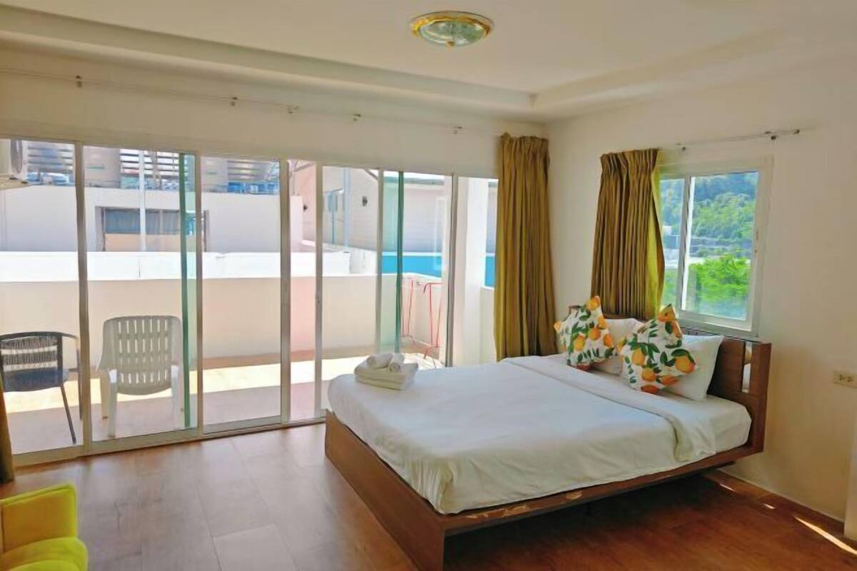 A bedroom with a wooden bed, a sliding glass door to a balcony, and a view of the sea.
