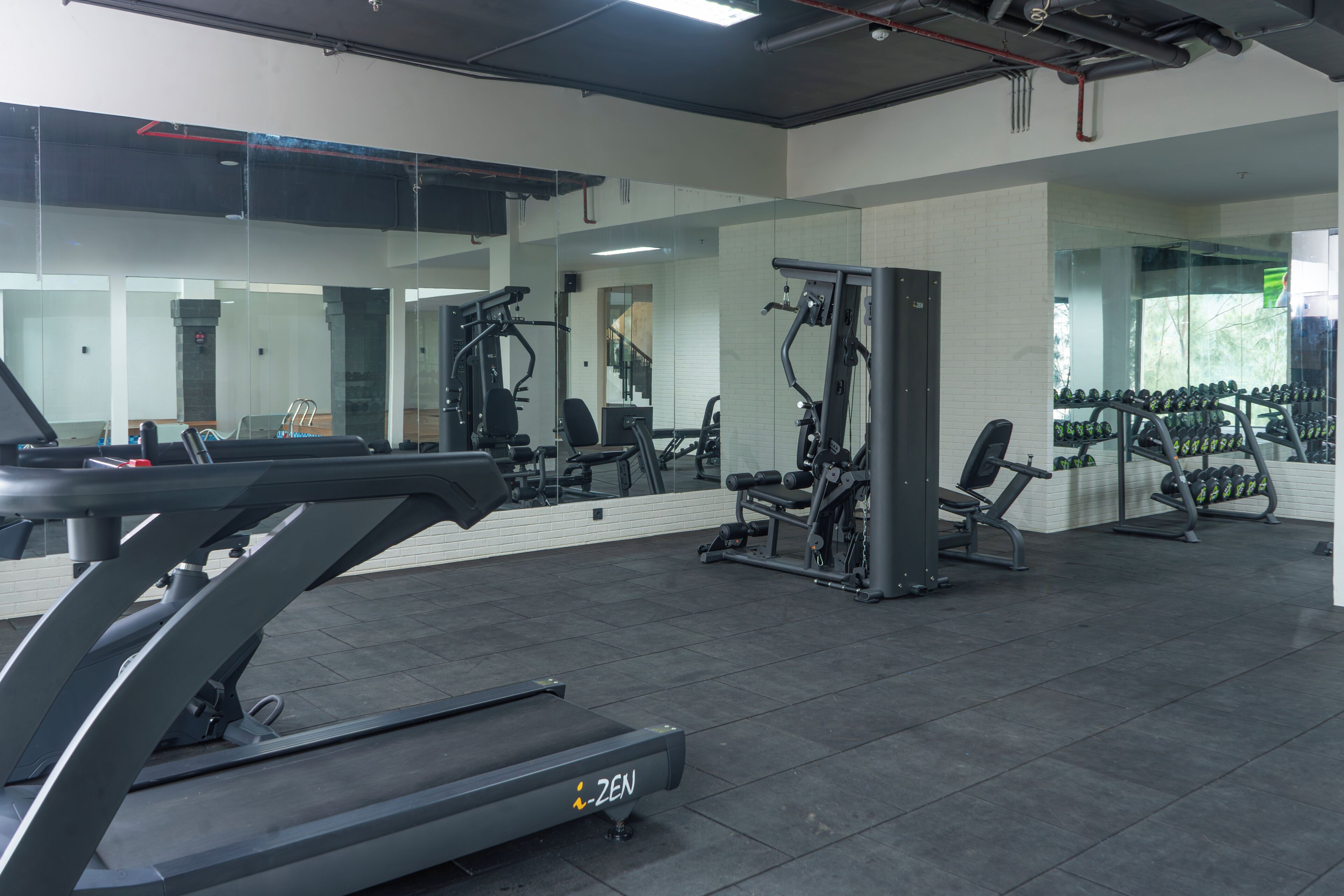 A gym with exercise equipment, a treadmill, and a mirrored wall.