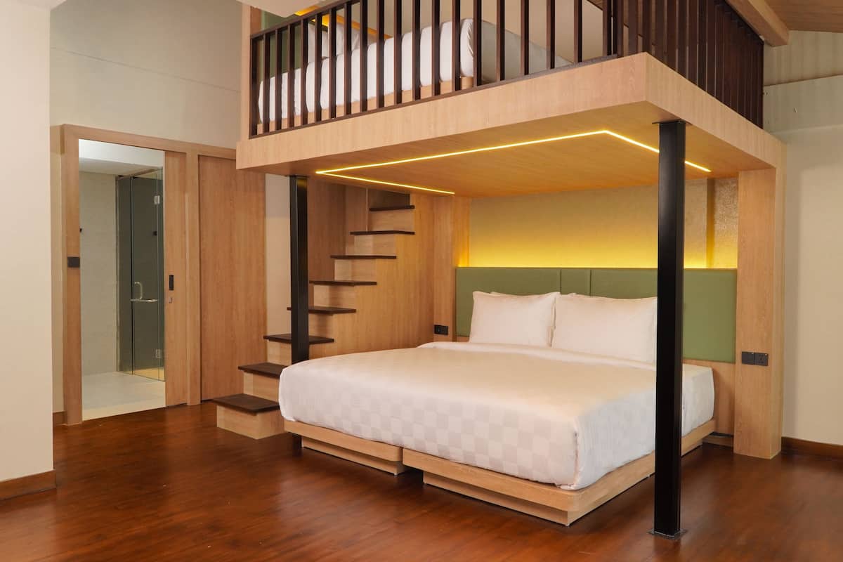 Un dormitorio moderno con cama de altillo, escalera de madera y una mesita.