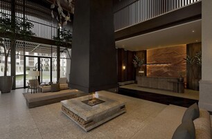 Un vestíbulo espacioso con una zona de estar central, un mostrador de recepción y un amplio ventanal que ofrece vistas del exterior del edificio.