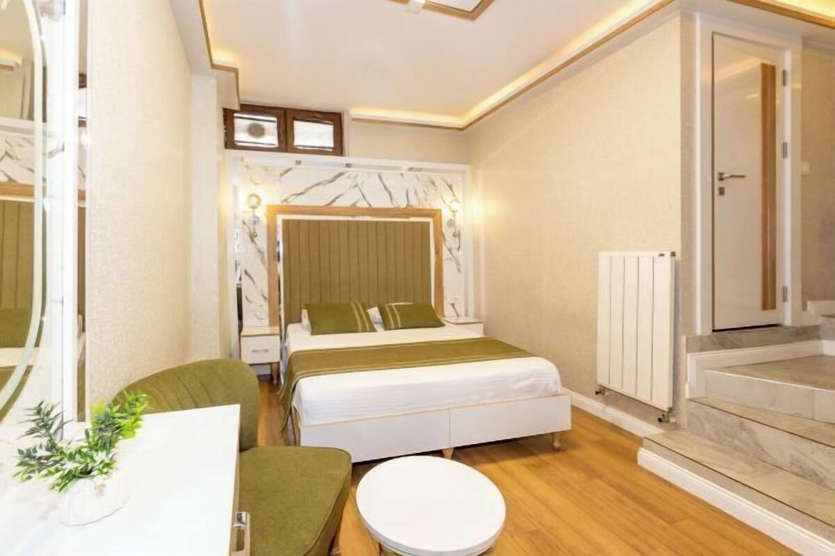 A hotel room with a bed, a round table, a chair, and a staircase.