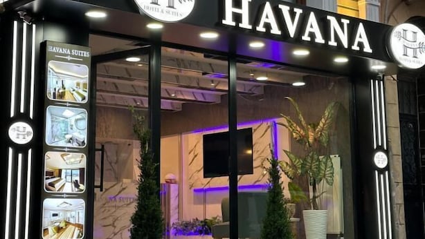 The exterior of the Havana Hotel & Suites with a modern facade, illuminated signage, and a view of the interior through the glass doors. - Havana Hotel Suites (Istanbul)