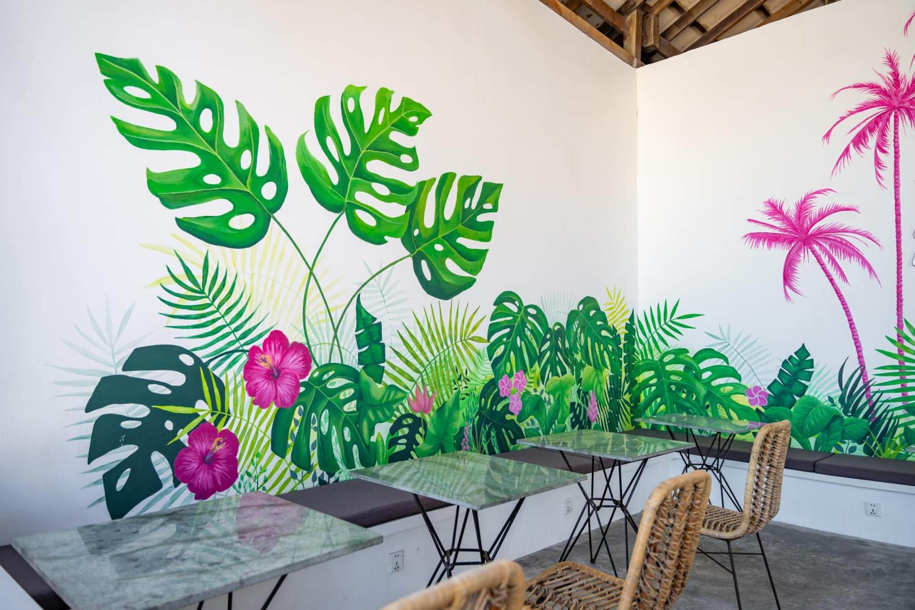 A dining area with a mural of tropical plants, tables, and chairs.