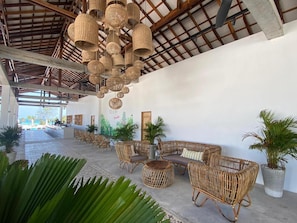 A covered outdoor seating area with wicker furniture and hanging light fixtures. - You Me Resort (Koh Rong)