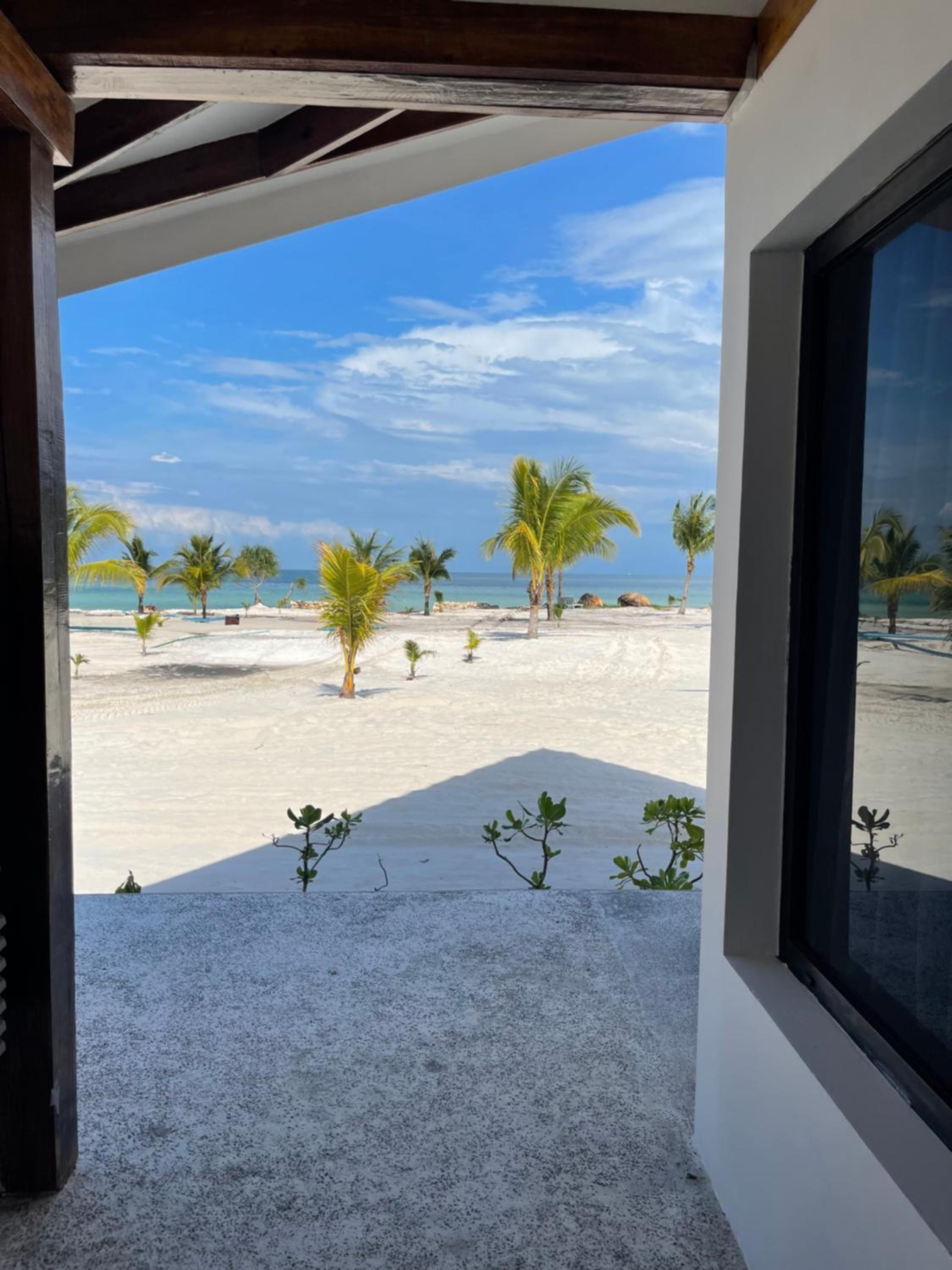 Vista de la playa desde un espacio al aire libre techado, con cielo despejado.