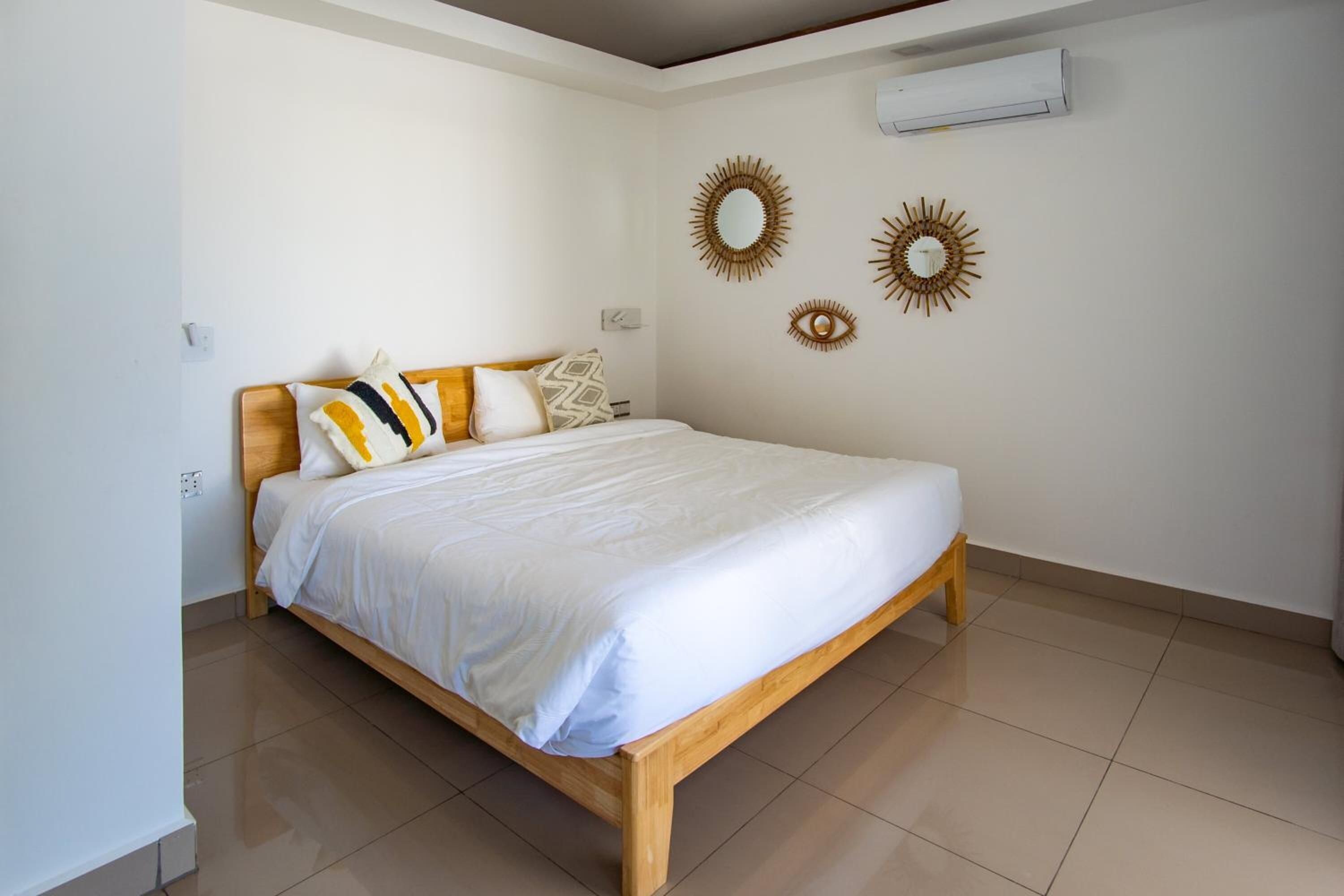 A bedroom with a wooden bed, white bedding, and decorative wall mirrors.
