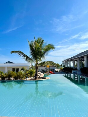 A swimming pool with a palm tree, a slide, and a covered area. - You Me Resort (Koh Rong)