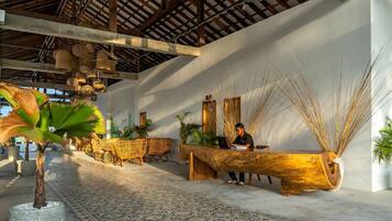 A reception area with a wooden reception desk, wicker chairs, and a patterned floor.