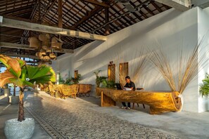 A reception area with a wooden reception desk, wicker chairs, and a patterned floor. - You Me Resort (Koh Rong)