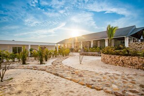 A resort with a stone pathway leading to a covered area with palm trees and a clear sky. - You Me Resort (Koh Rong)