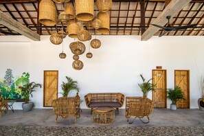 A room with wicker furniture, hanging baskets, and wooden doors. - You Me Resort (Koh Rong)