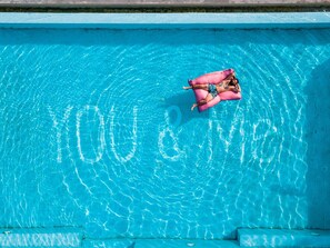 A person lying on a pink float in a clear blue pool. - You Me Resort (Koh Rong)