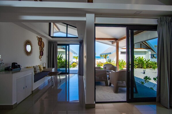 A modern hotel room with a large sliding glass door leading to a pool area. - You Me Resort (Koh Rong)