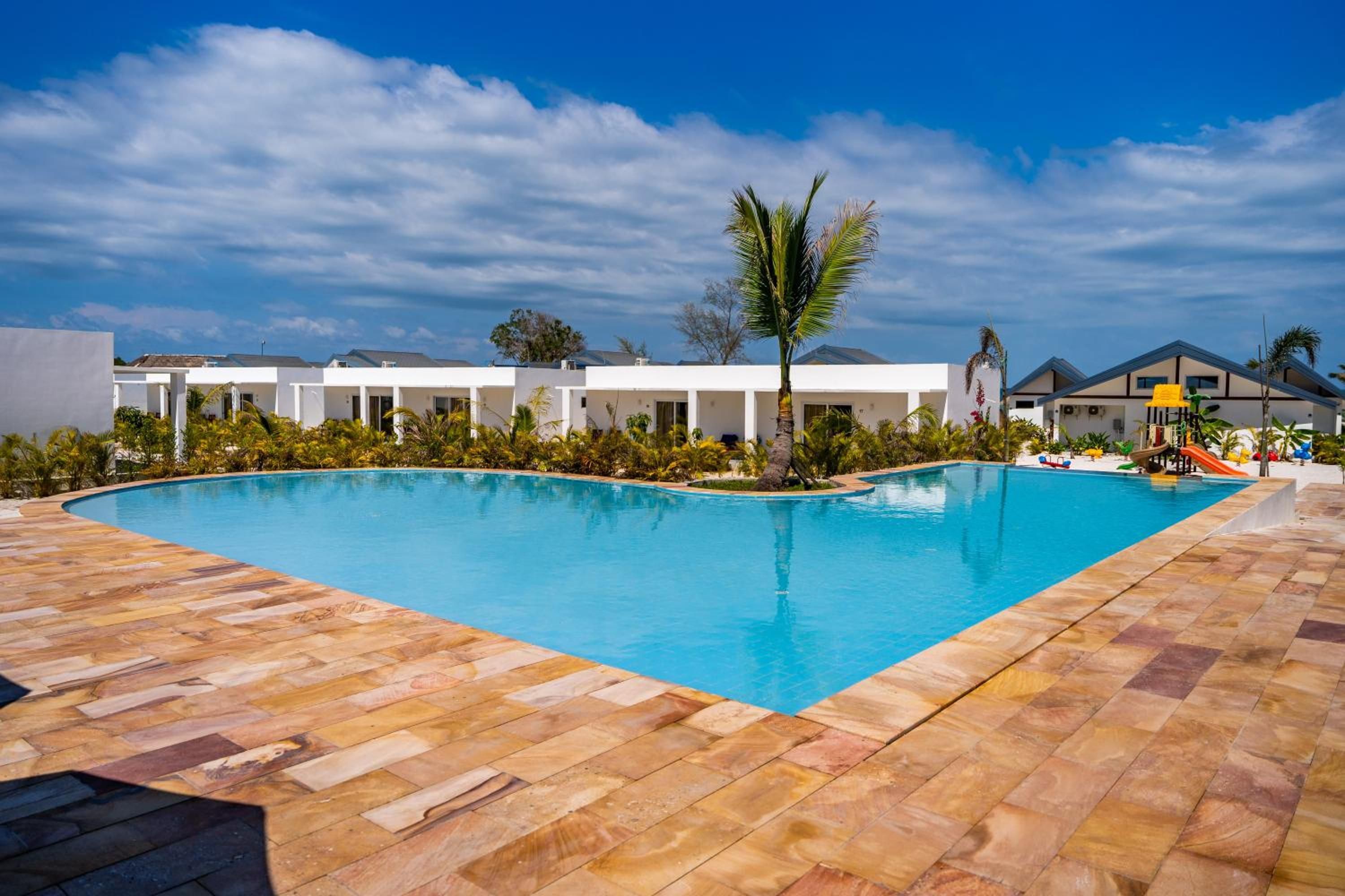 A swimming pool with a tiled deck, surrounded by buildings with a modern architectural style.