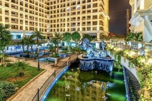 A hotel courtyard with a central fountain, palm trees, and a pool.