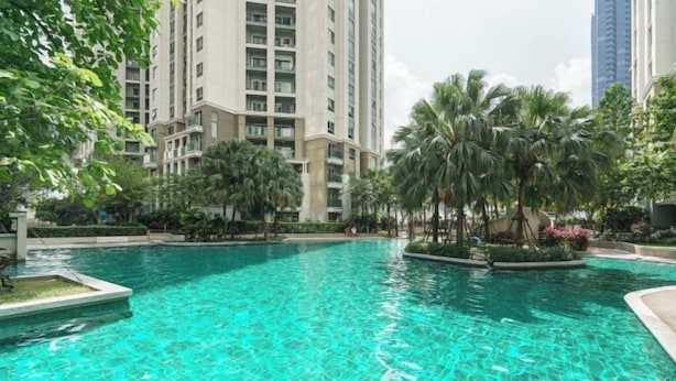 A swimming pool surrounded by palm trees and high-rise buildings. - Bella Rama 9 Apartment Bangkok [near central rama 9 shopping mall + Phra Rama 9 subway station] (Bangkok)