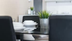 A dining table with white plates and a metal container with green plants. - Bella Rama 9 Apartment Bangkok [near central rama 9 shopping mall + Phra Rama 9 subway station] (Bangkok)