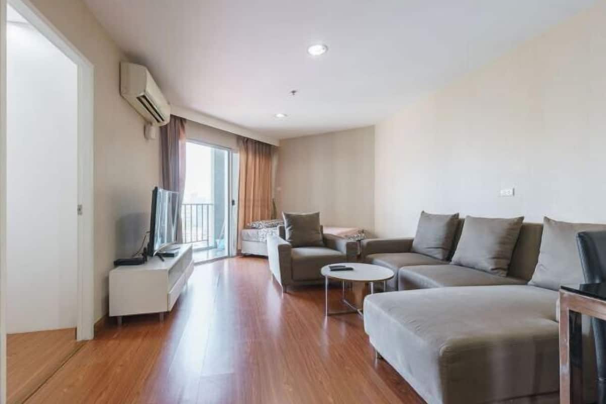 A modern living room with a sofa set, a coffee table, and a TV on a stand.