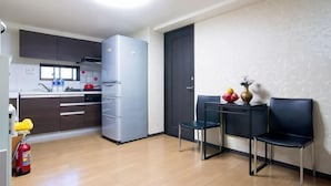 Una cucina moderna con frigorifero, un'area pranzo con sedie e un piccolo tavolo.
