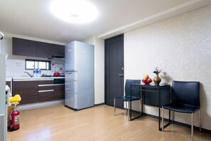 Eine moderne Küche mit Kühlschrank, eine Essecke mit Stühlen und einem kleinen Tisch.