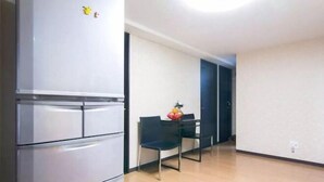 Una cucina con un frigorifero, un tavolo da pranzo con sedie e una ciotola di frutta.