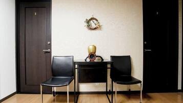 A room with two black chairs, a small table with a decorative item, and two doors.
