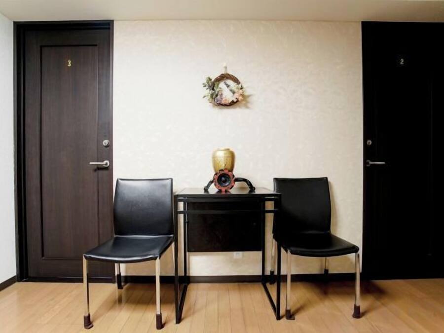A room with two black chairs, a small table with a decorative item, and two doors.