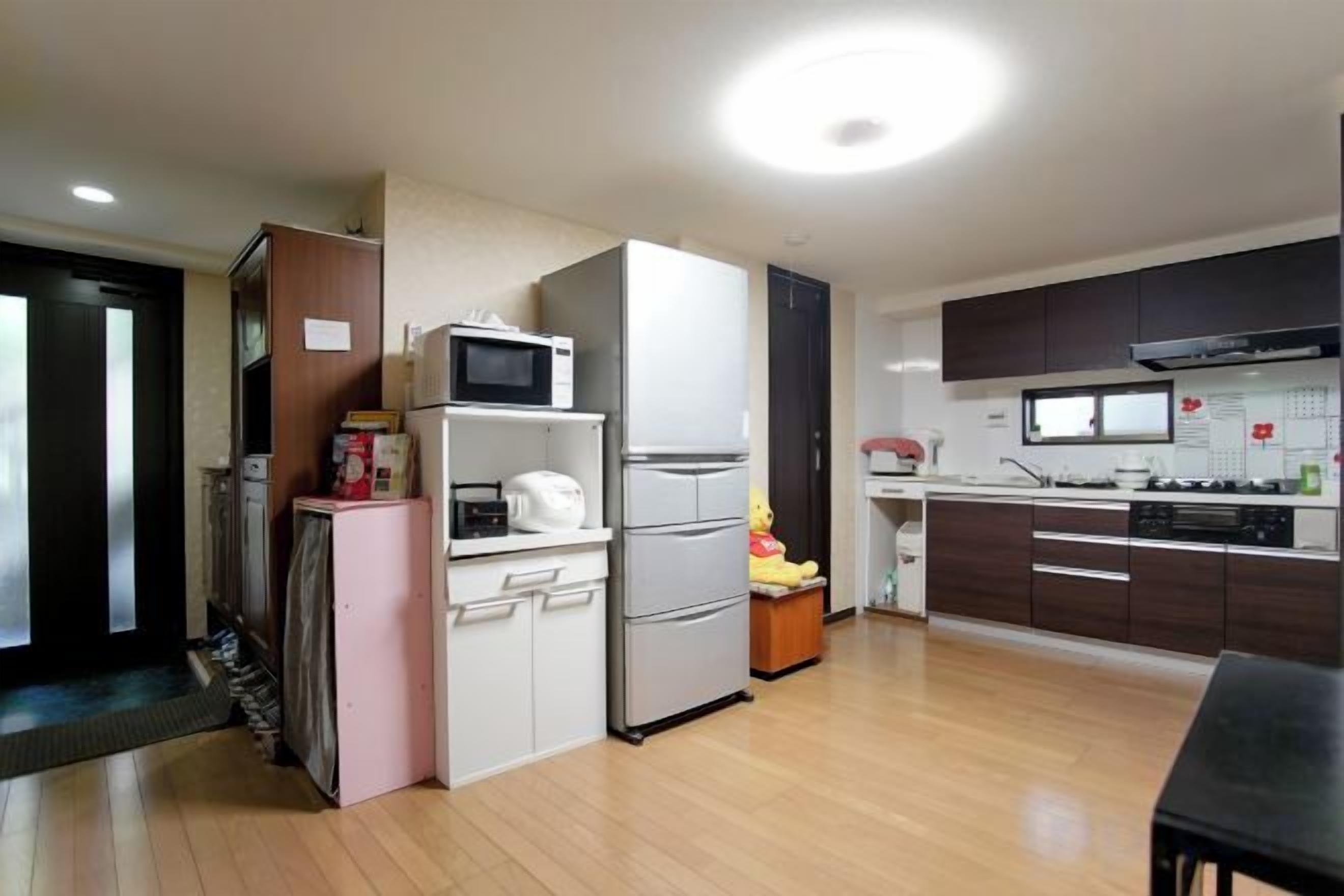 Une cuisine moderne équipée d’un réfrigérateur, d’un four à micro-ondes et d’une cuisinière, avec un plancher en bois et un coin repas comprenant une table.